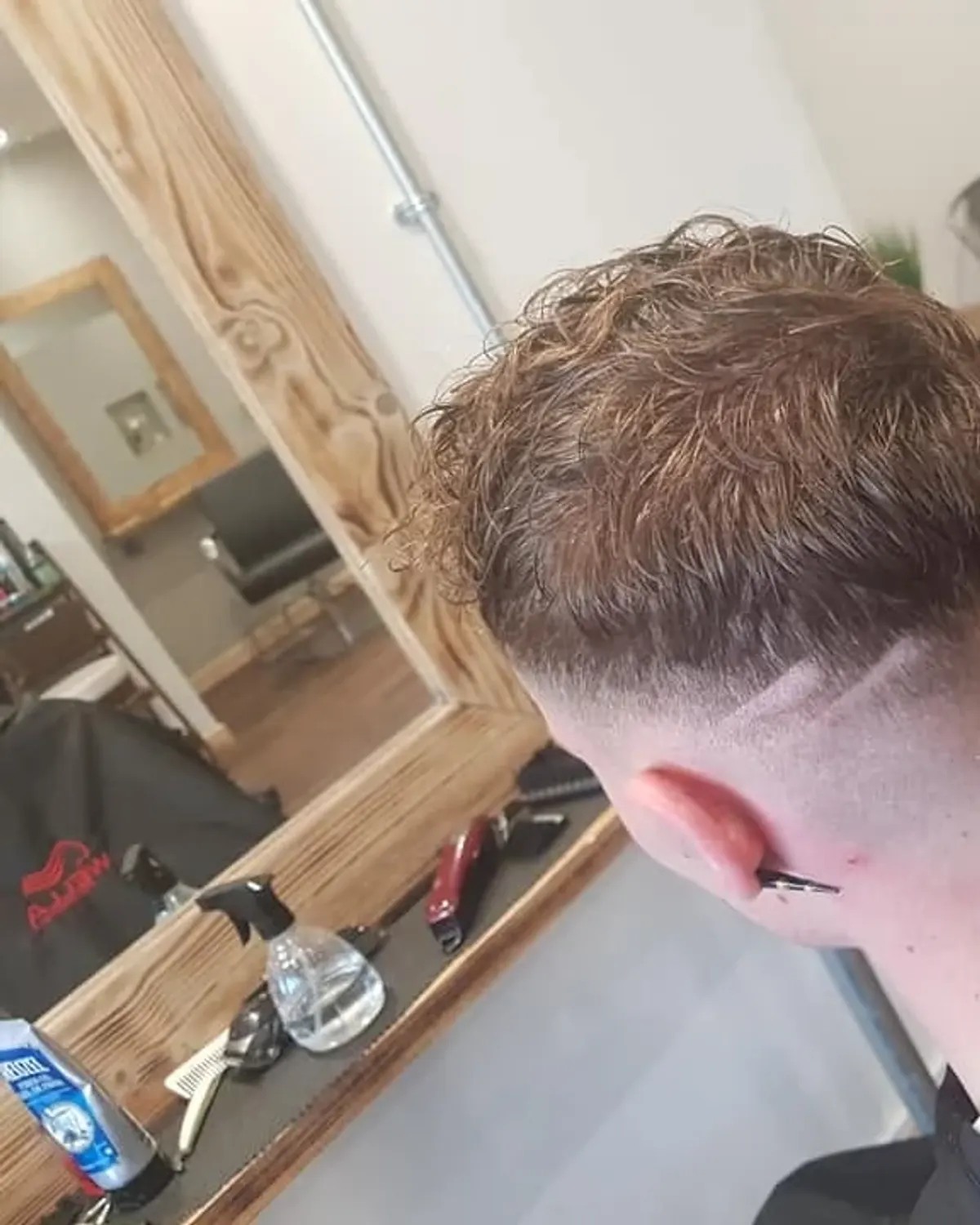 Curly crop with a shaved line design and skin fade, cut at Primo Hair Lounge Ipswich